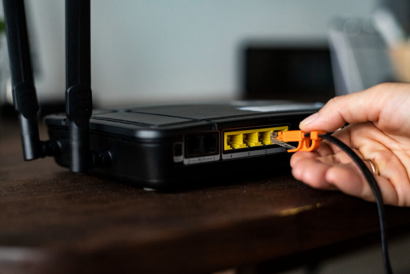 man plugging in an ethernet cable to a wireless router