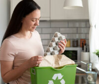 Woman holding egg carton on dustbin