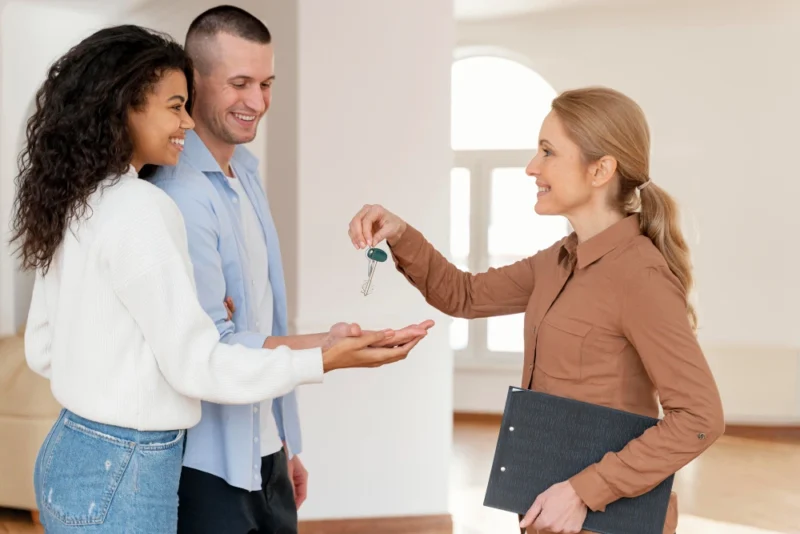 Female realtor handing couple the keys to their new home